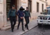 Detenido un empleado de banca en Gandia por estafar 25.000 euros Dos agentes de la Guardia Civil escoltan a un hombre esposado a la salida del puesto principal de Gandia