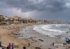 El fenómeno del meteotsunami: qué ha ocurrido en Santa Pola y cuál es el riesgo real Playa durante una tormenta con rayos en el cielo nublado, olas en el mar y gente observando desde el paseo marítimo