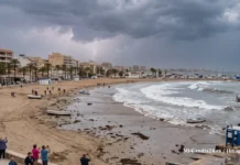 El fenómeno del meteotsunami: qué ha ocurrido en Santa Pola y cuál es el riesgo real Playa durante una tormenta con rayos en el cielo nublado, olas en el mar y gente observando desde el paseo marítimo