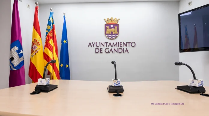 Sala de prensa del Ayuntamiento de Gandia con banderas oficiales y micrófonos sobre la mesa
