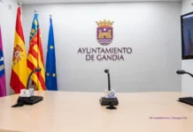Gandia – primer refugio climático en la primera línea de la playa Sala de prensa del Ayuntamiento de Gandia con banderas oficiales y micrófonos sobre la mesa